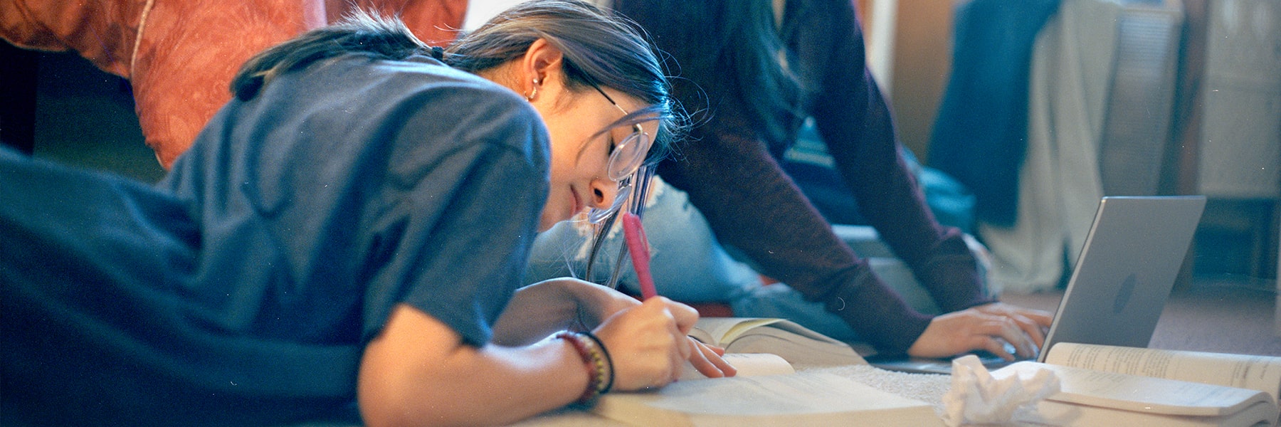 Student in residence hall writing in a book.
