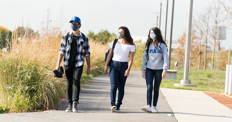 Students wearing masks walk the HarborWalk
