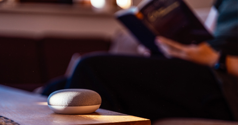 Smart home AI device with man reading book in background